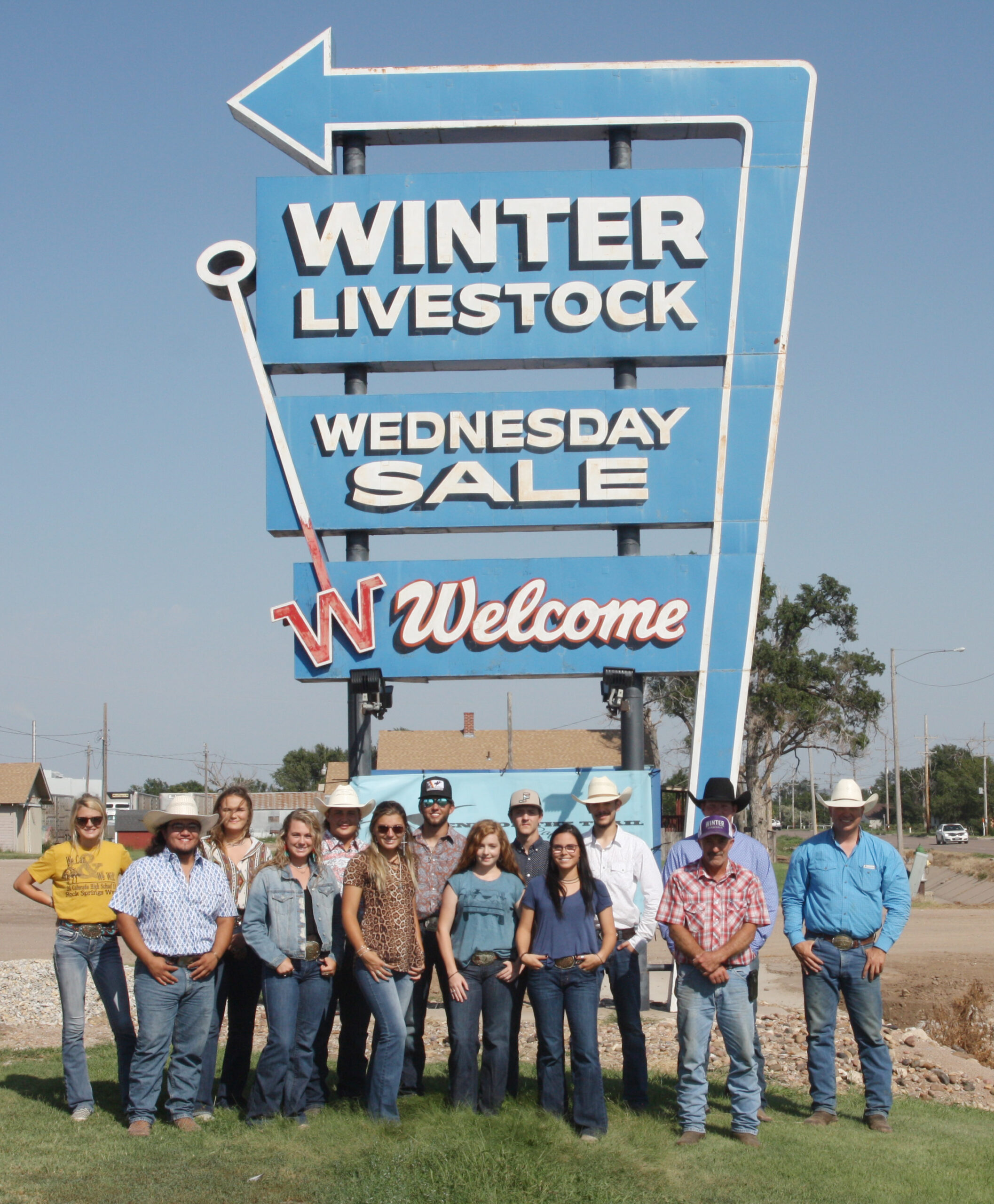 DC3 rodeo team poses with their coach, Gabe Burrows and members of Winter Livestock in front of the Winter Livestock sign