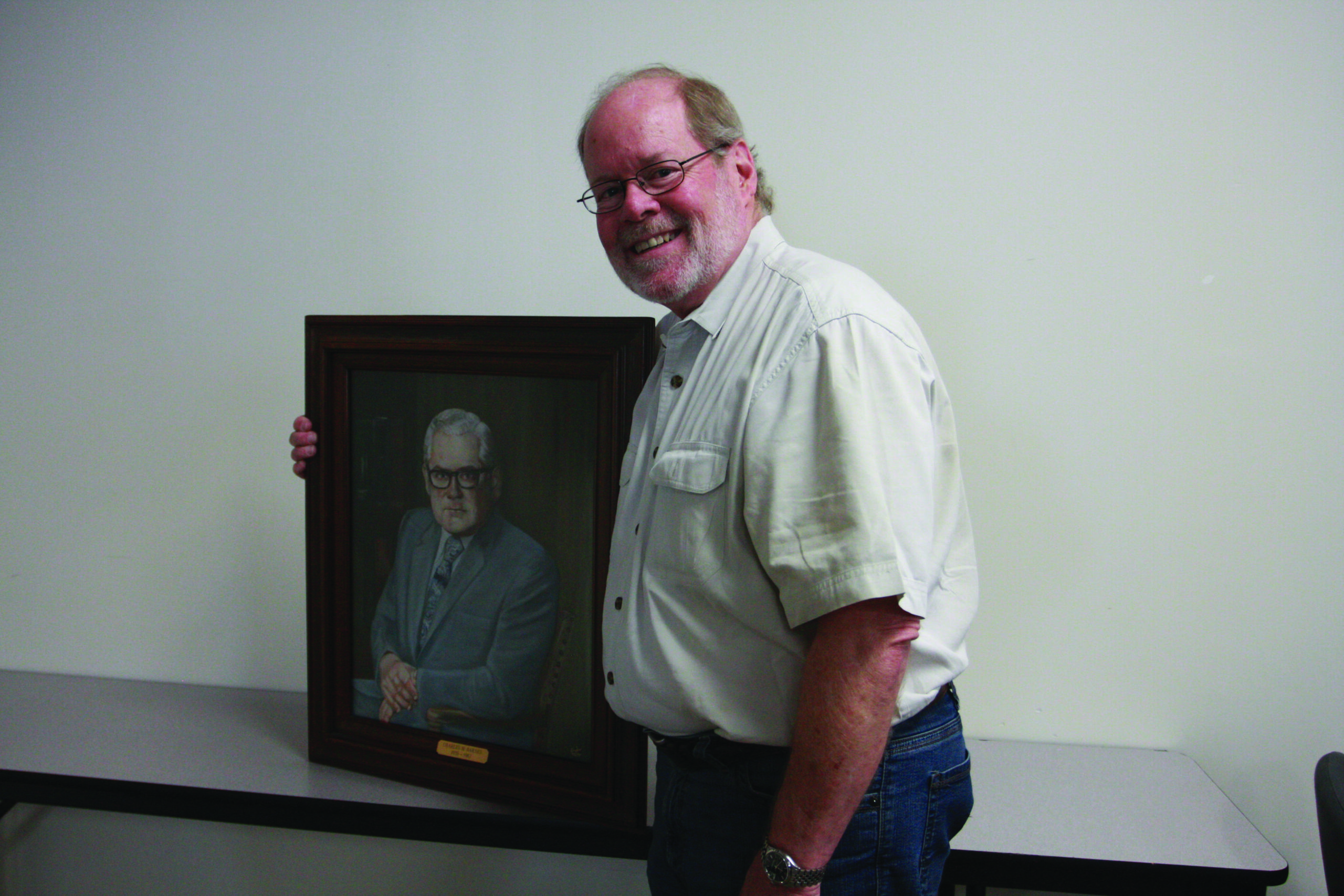 Roger Barnes poses with a painting of his father Charles Barnes, former DC3 President